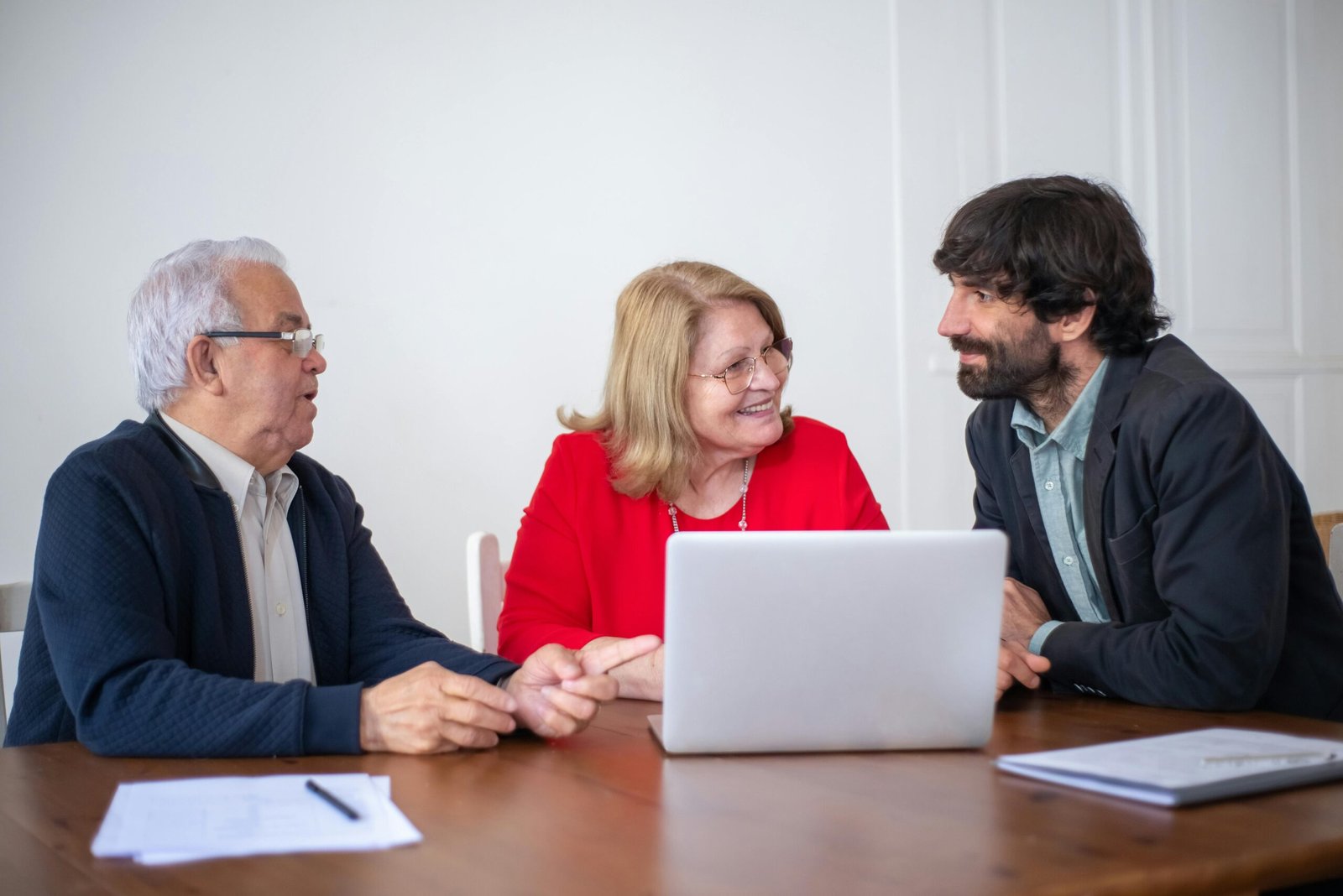 Three people discussing over a laptop.